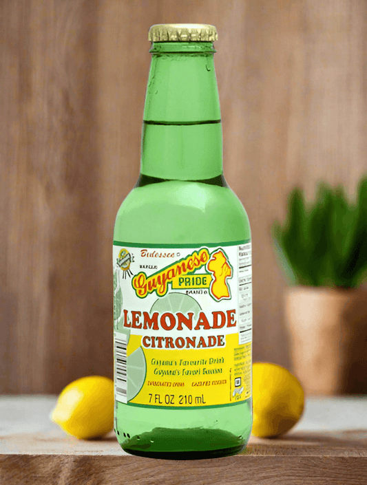 Guyanese Lemonade Drink 210ml bottle on wooden table, surrounded by fresh lemons and greenery.